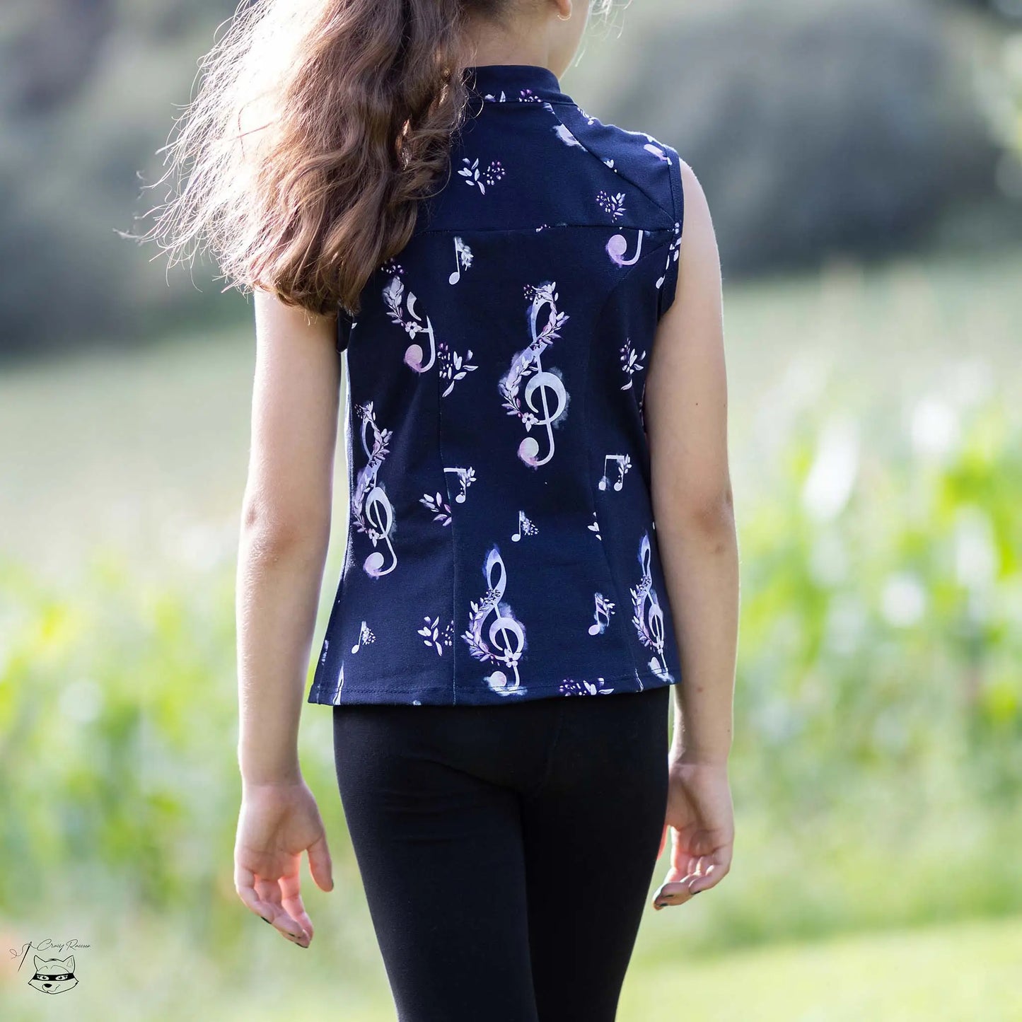 Vue de dos d’une enfant portant un haut noir à motif musical, tête tournée sur le côté - patron de couture Gaby de Kandix