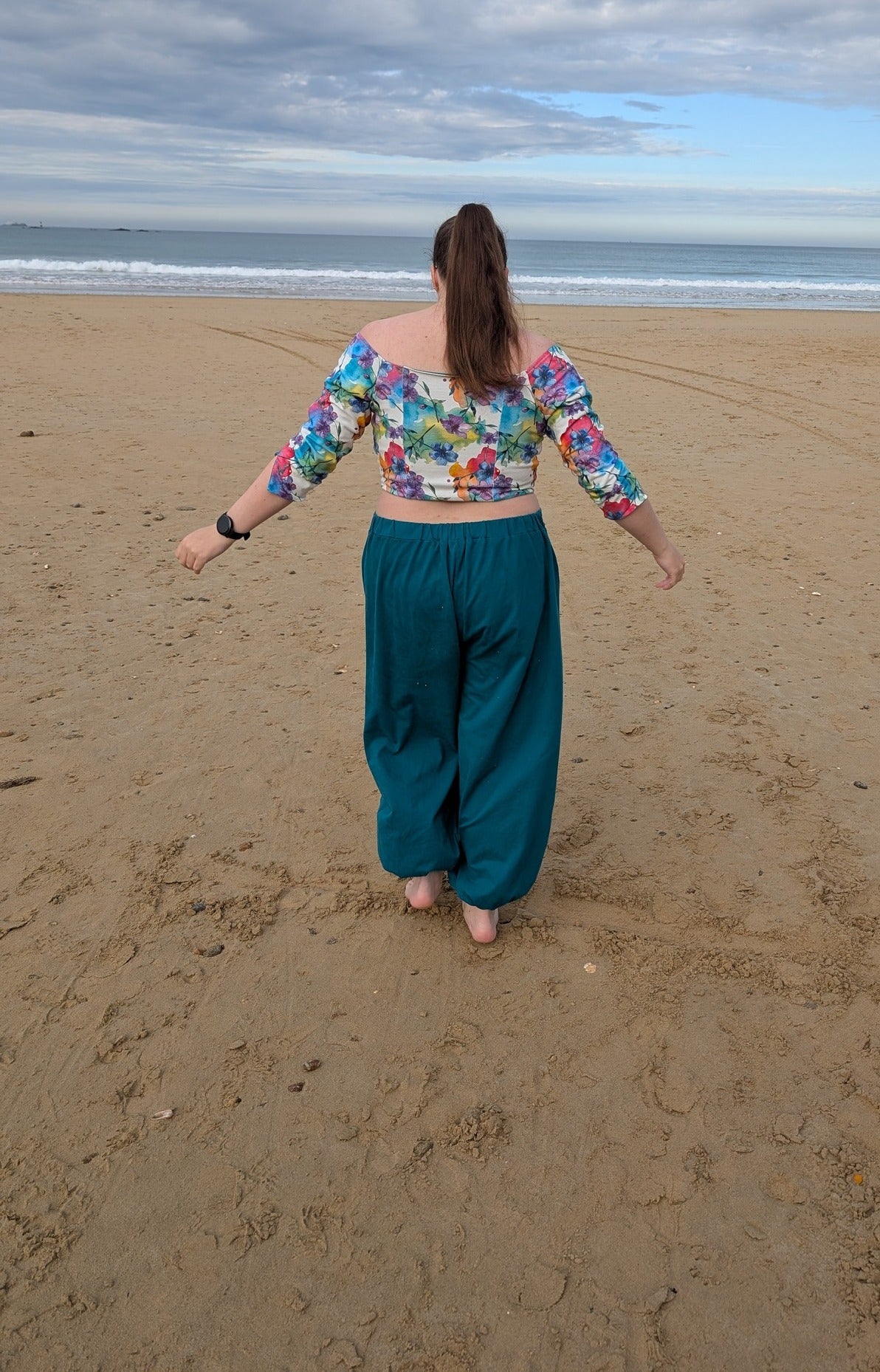 Ensemble Yasmine femme, top fleuri multicolore avec dos en jersey et pantalon vert canard, vue de dos à la plage – patron Kandix