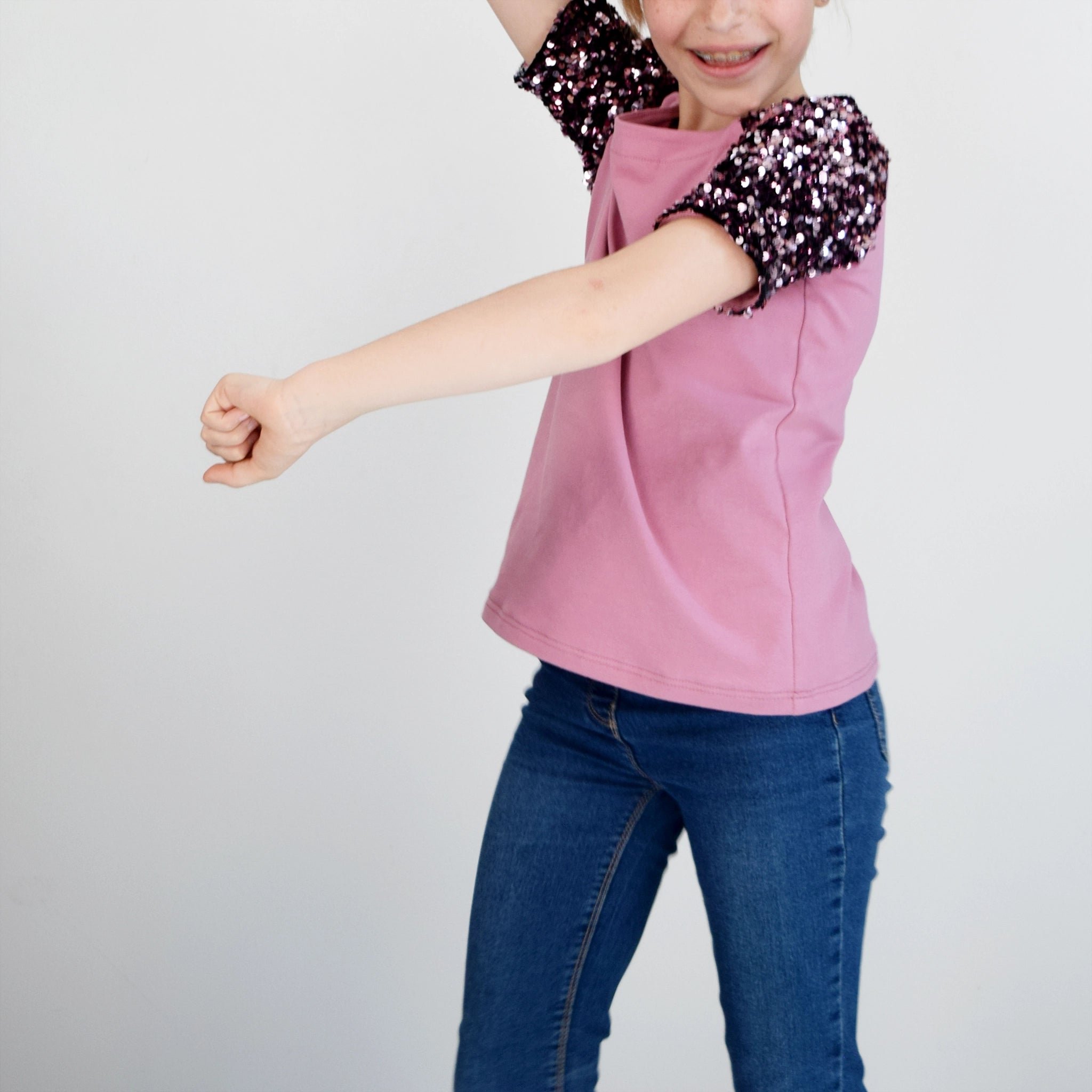T-shirt raglan enfant rose avec manches à sequins en pose dynamique – patron de couture TAO de Kandix