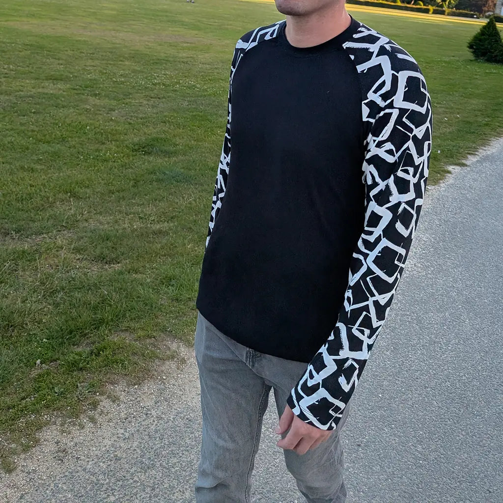 Homme en t-shirt raglan noir à manches longues imprimées, vu de face, marchant en extérieur – patron de couture Tao de Kandix