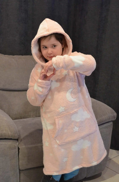 Enfant portant un sweat doudou rose à capuche imprimé étoiles et nuages, debout devant un canapé en formant un cœur avec les mains - patron de couture Casimir de Kandix
