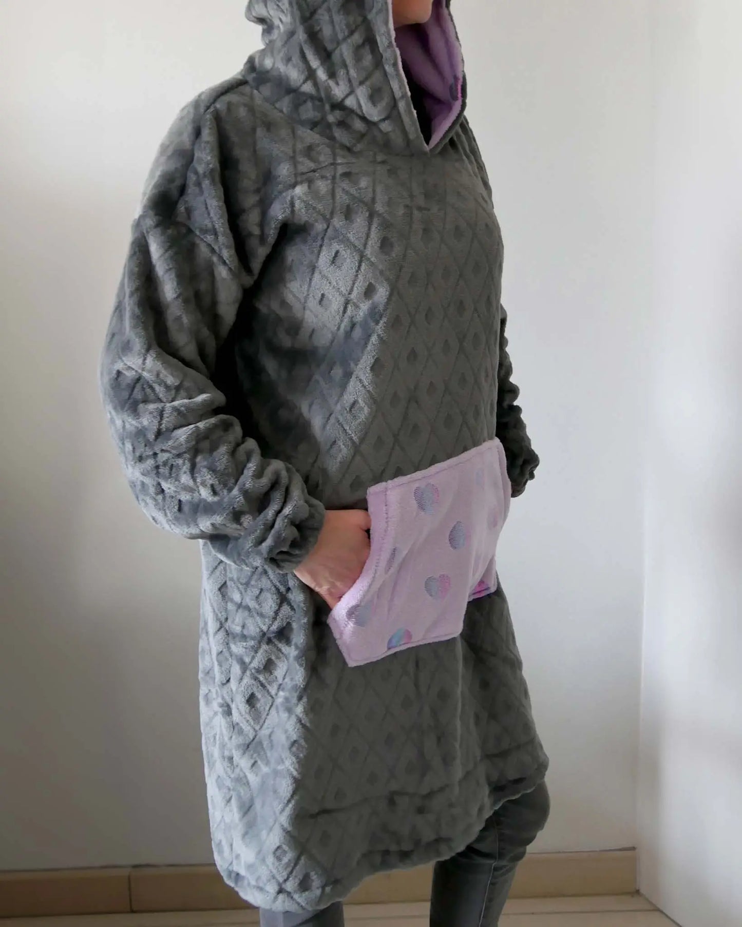 Femme en sweat polaire gris à capuche et poche à motifs cœurs, vue de profil, les mains dans la poche - patron de couture Casimir de Kandix
