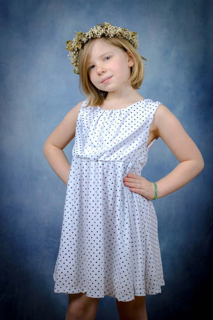 Robe blanche enfant en tissu à sequins, vue de face avec les mains sur les hanches, fond bleu studio - patron de couture Cylia de Kandix