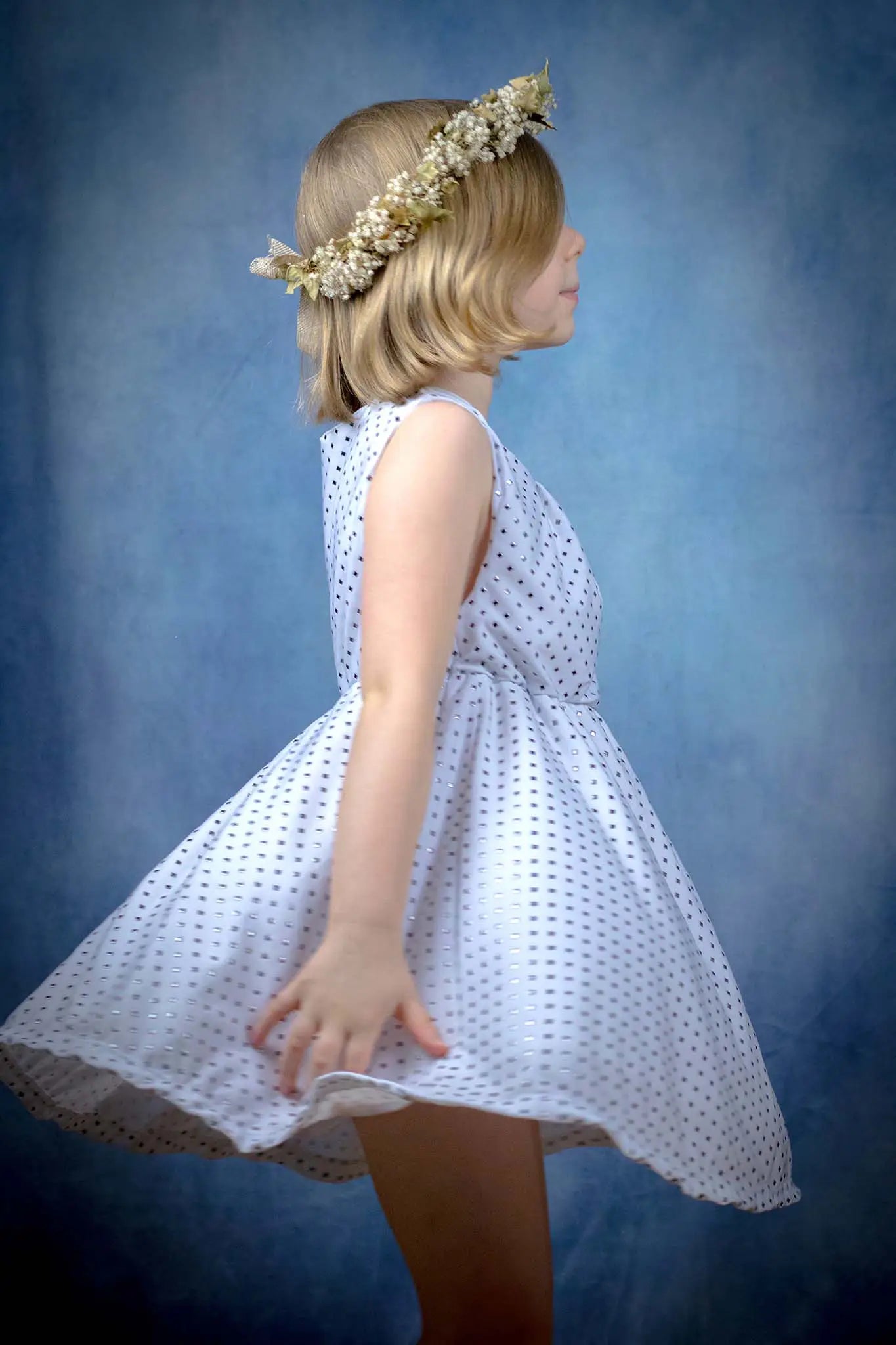 Robe blanche pour enfant en pleine rotation, vue de profil, couronne de fleurs en accessoire - patron de couture Cylia de Kandix