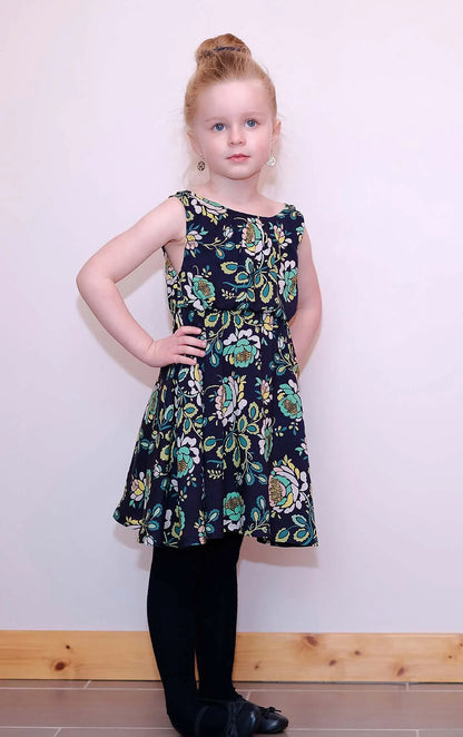 Fillette rousse debout, main sur la taille, en robe bleu marine fleurie – patron de couture Cylia de Kandix