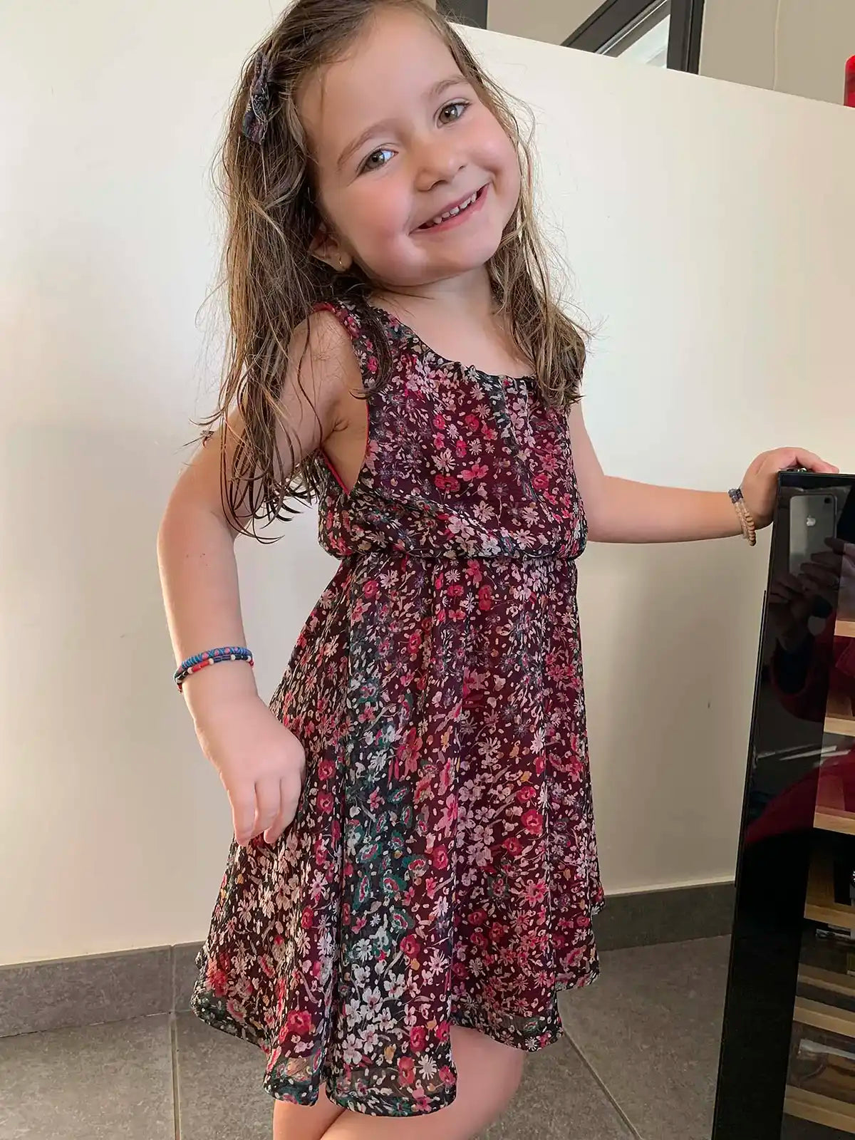 Robe d’enfant à fleurs bordeaux, vue trois-quarts avec sourire et pose naturelle – patron de couture Cylia de Kandix