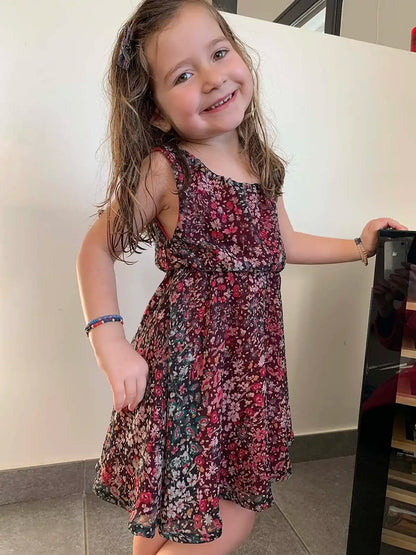 Robe d’enfant à fleurs bordeaux, vue trois-quarts avec sourire et pose naturelle – patron de couture Cylia de Kandix