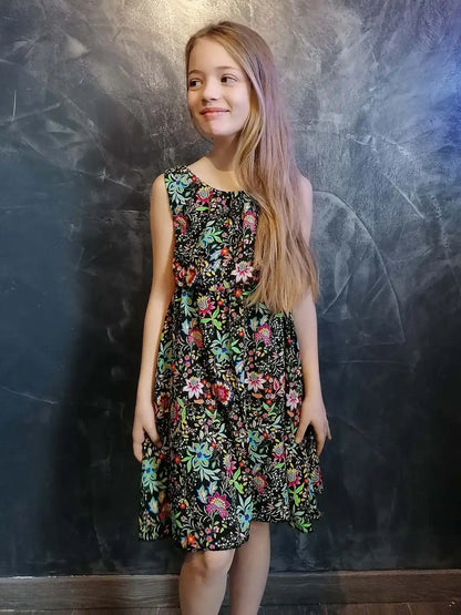 Fillette en robe Cylia noire à fleurs, tenant la jupe en tournant – patron de couture Kandix