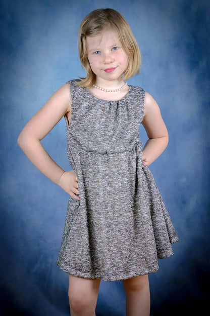Robe enfant en maille grise pailletée portée avec les mains sur la taille – patron de couture Cylia de Kandix