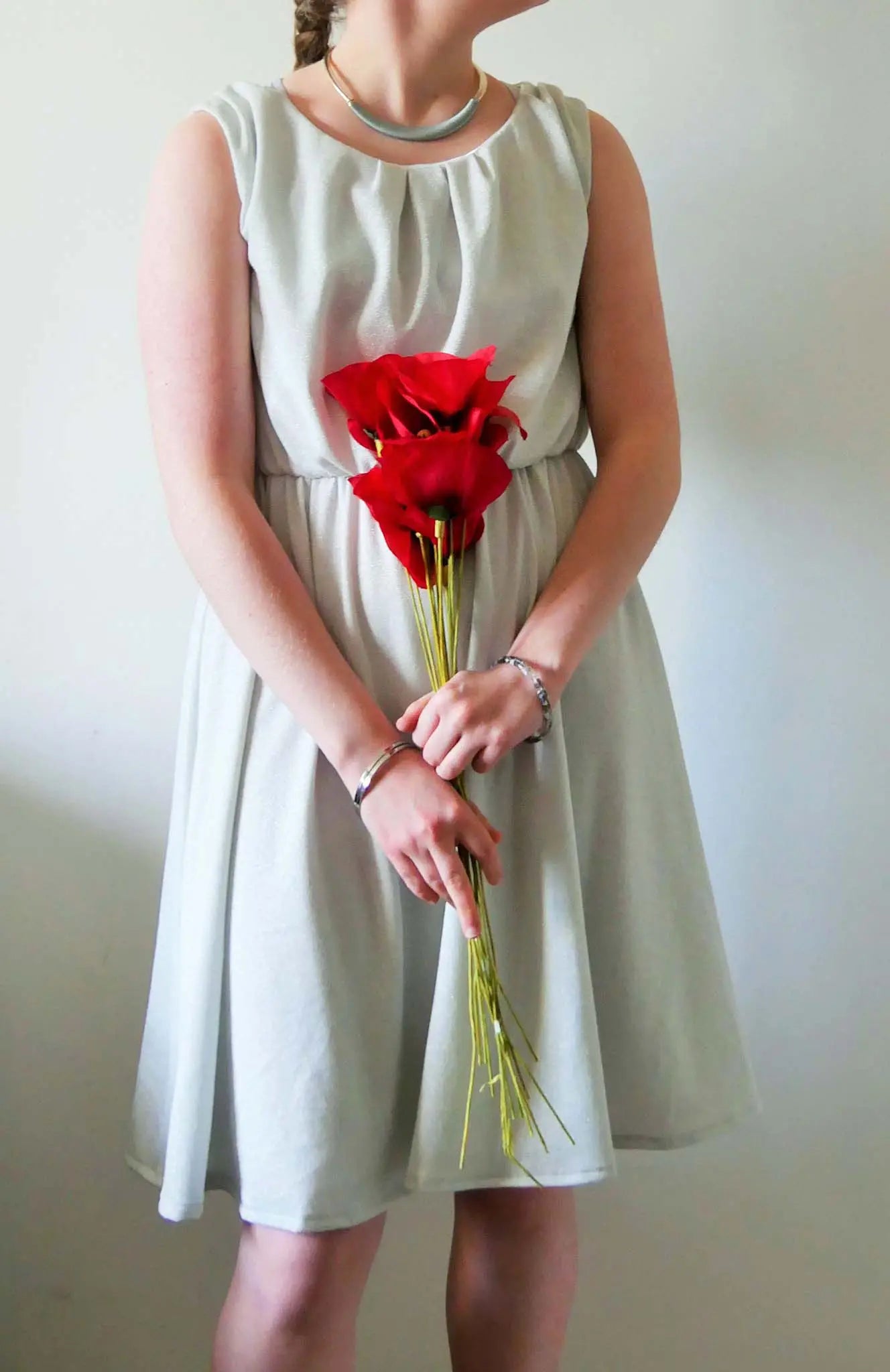 Robe gris clair portée avec un bouquet de fleurs rouges, vue de face – patron de couture Cylia de Kandix