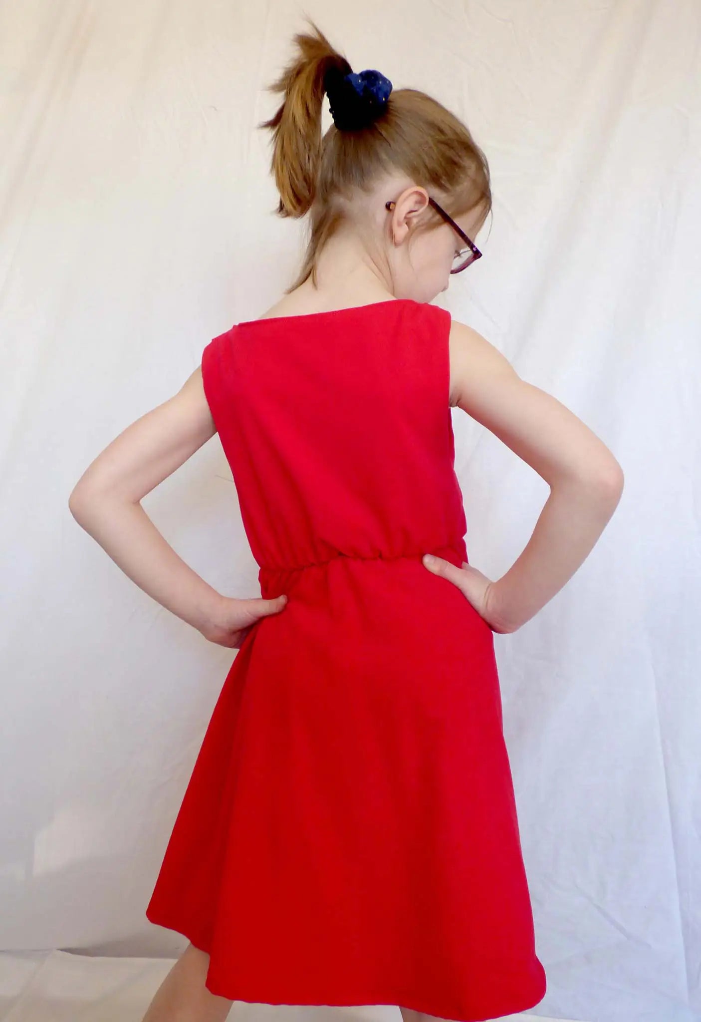 Vue de dos d’une fillette en robe rouge avec les mains sur les hanches – patron de couture Cylia de Kandix