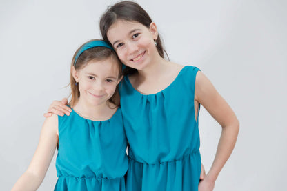 Portrait d'enfants souriantes en robe turquoise, main posée sur l'épaule – patron de couture Cylia de Kandix