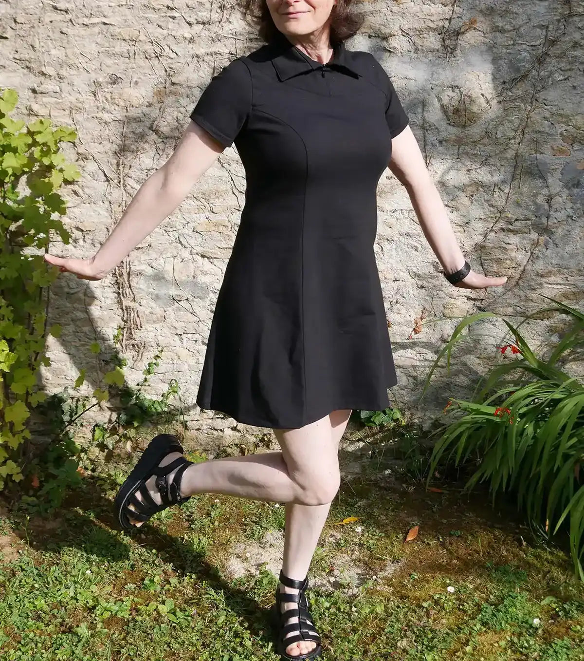 Femme en robe noire col polo, debout en équilibre, bras ouverts - patron de couture Gaby de Kandix