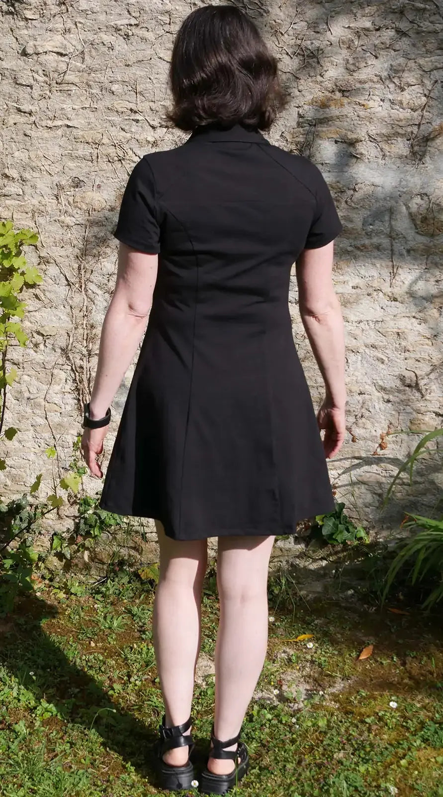 Vue dos d'une femme en robe noire col polo, jambes serrées - patron de couture Gaby de Kandix