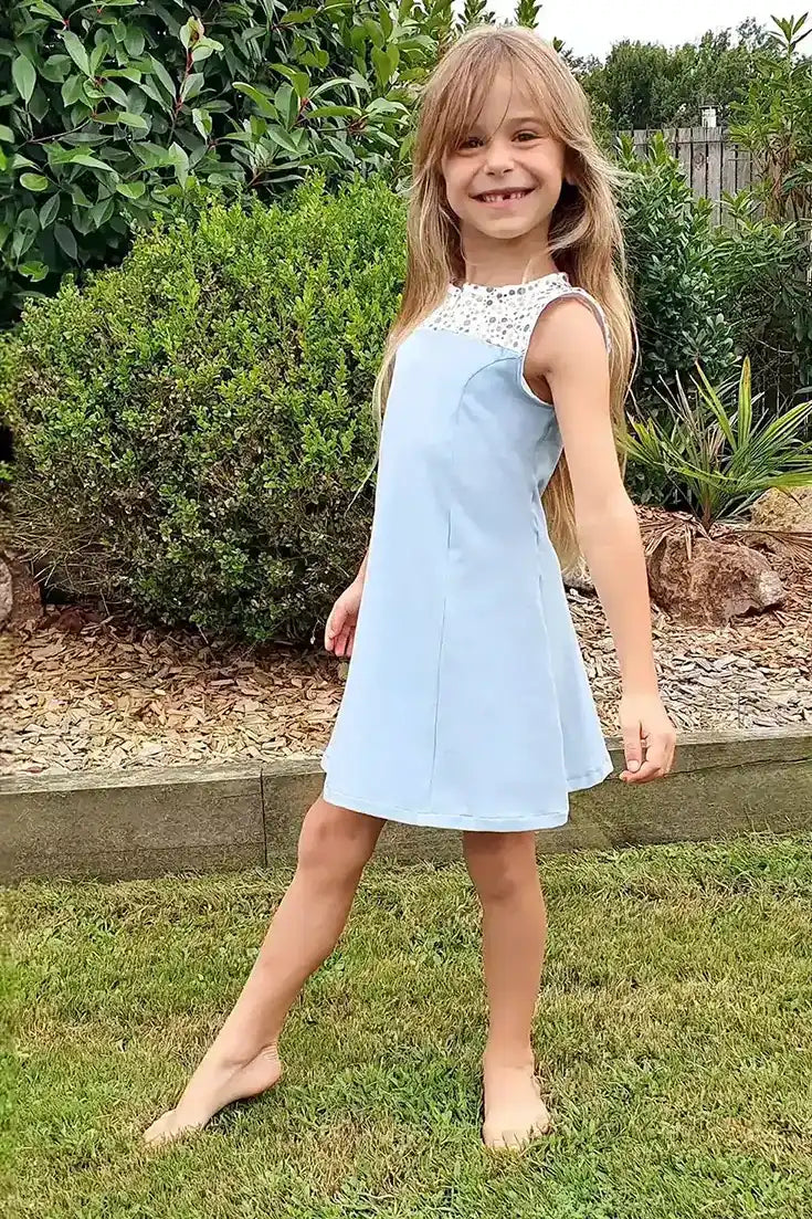 Robe enfant bleu ciel avec empiècement en dentelle blanche, portée par une fillette souriante - patron de couture Gaby de Kandix