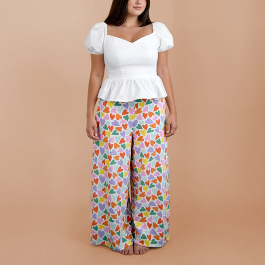 Ensemble Yasmine femme composé d’un top blanc et d’un pantalon imprimé cœurs multicolores porté pieds nus, vue de face – patron Kandix