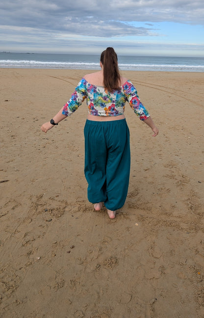 Ensemble Yasmine femme, top fleuri multicolore avec dos en jersey et pantalon vert canard, vue de dos à la plage – patron Kandix