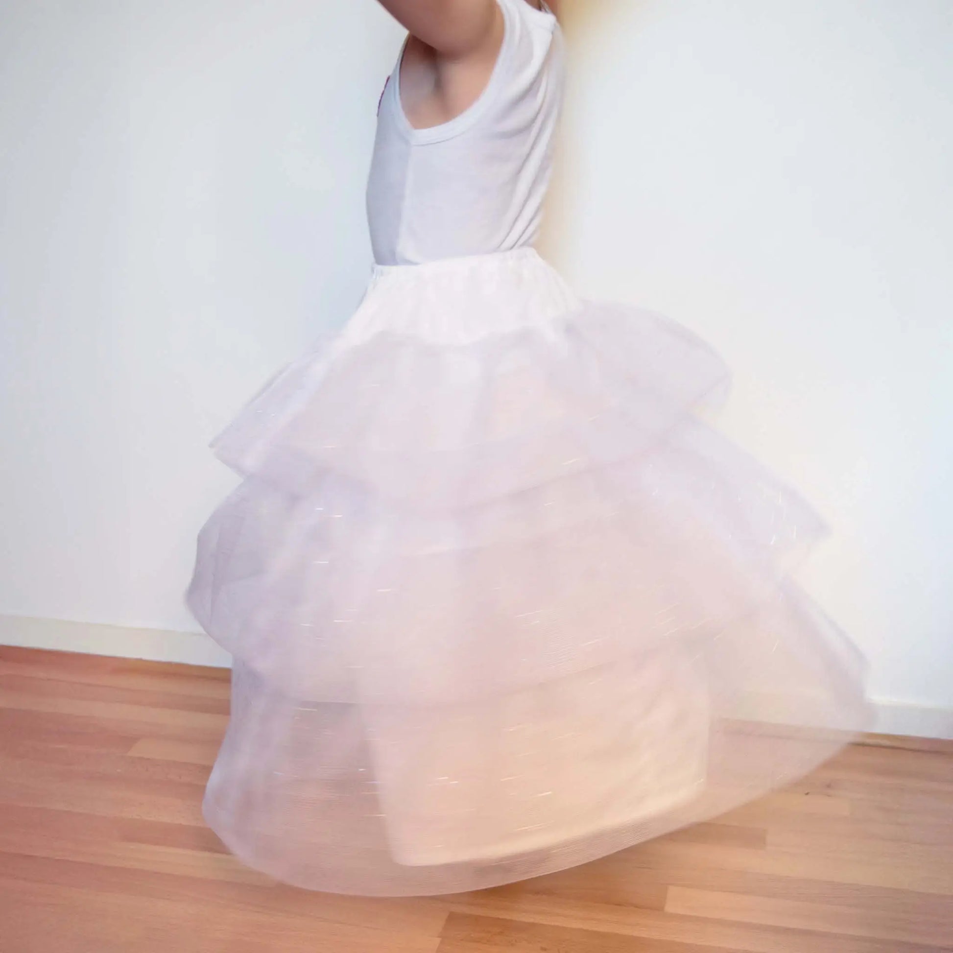 Petite fille tournant sur elle-même avec un jupon blanc en tulle pailleté – patron de couture Kandix