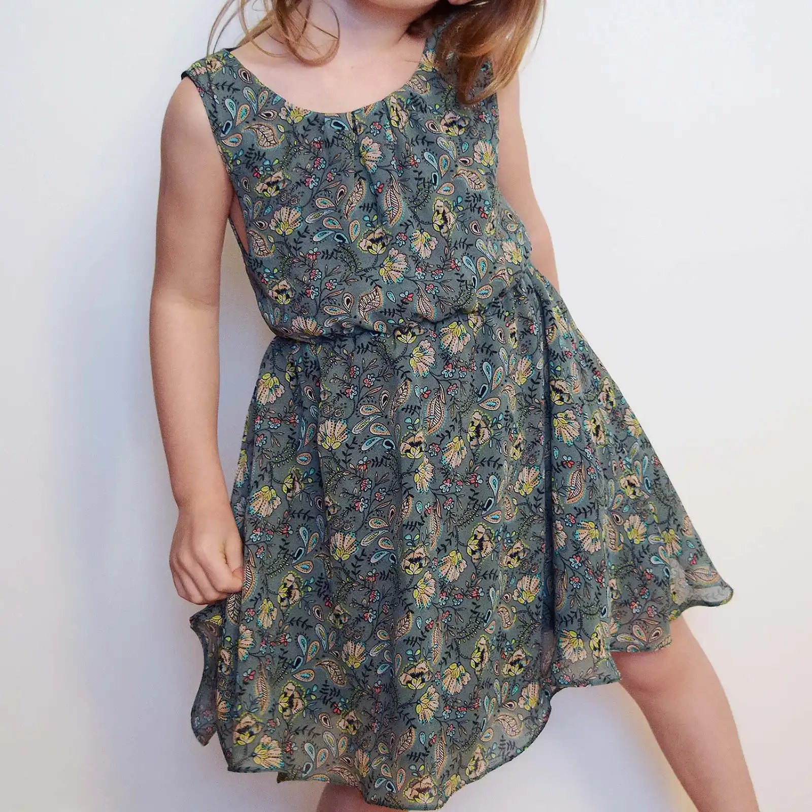 Enfant posant de face en robe Cylia imprimé fleuri, main sur la hanche – patron de couture Cylia de Kandix