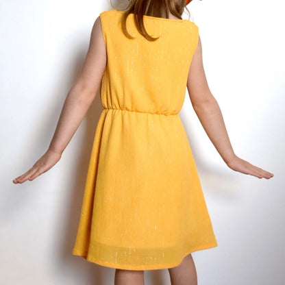 Robe jaune pour enfant vue de dos, tissu à fil lurex doré, bras étendus – patron de couture Cylia de Kandix