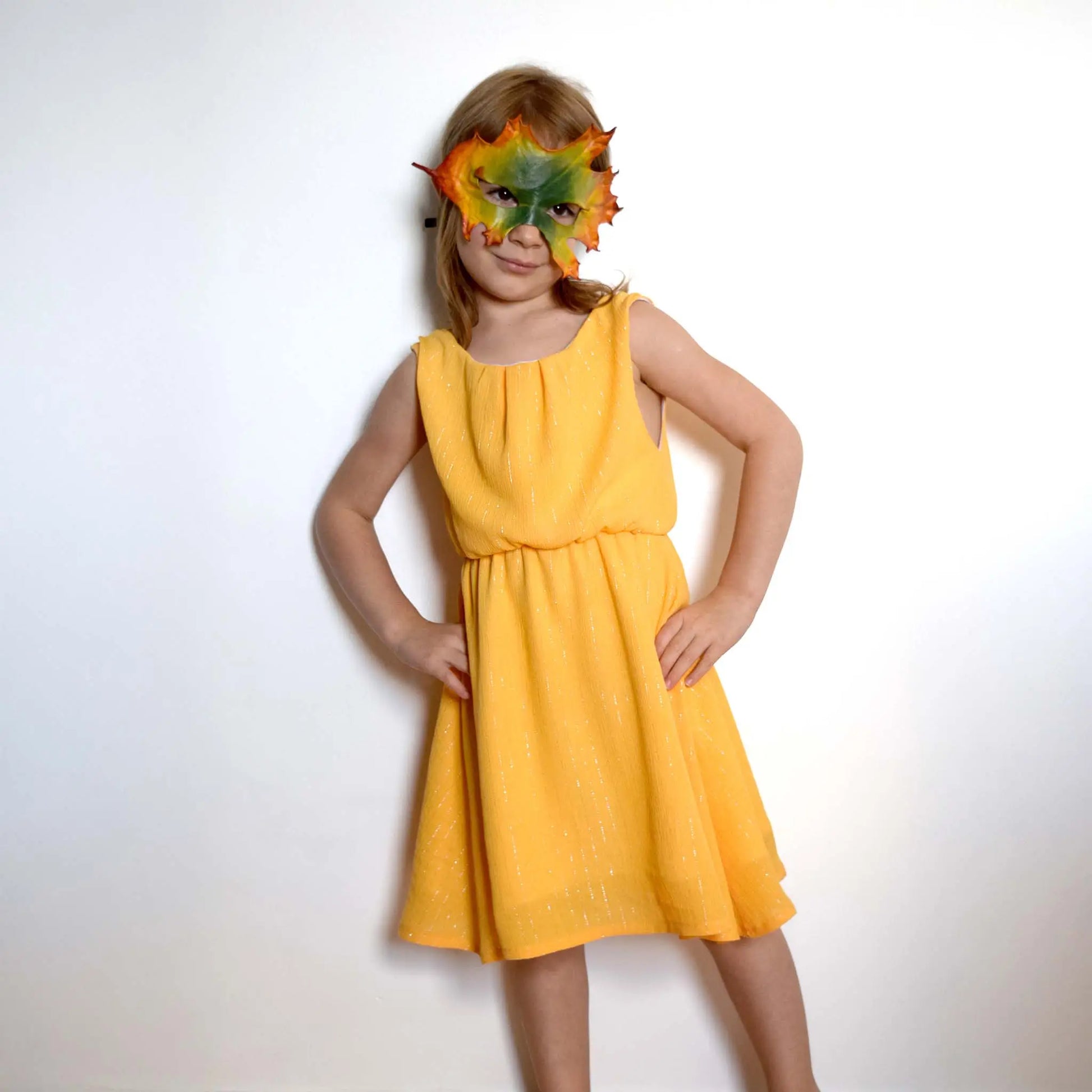 Fillette en robe jaune sans manches avec masque automnal, mains sur les hanches – patron de couture Cylia de Kandix