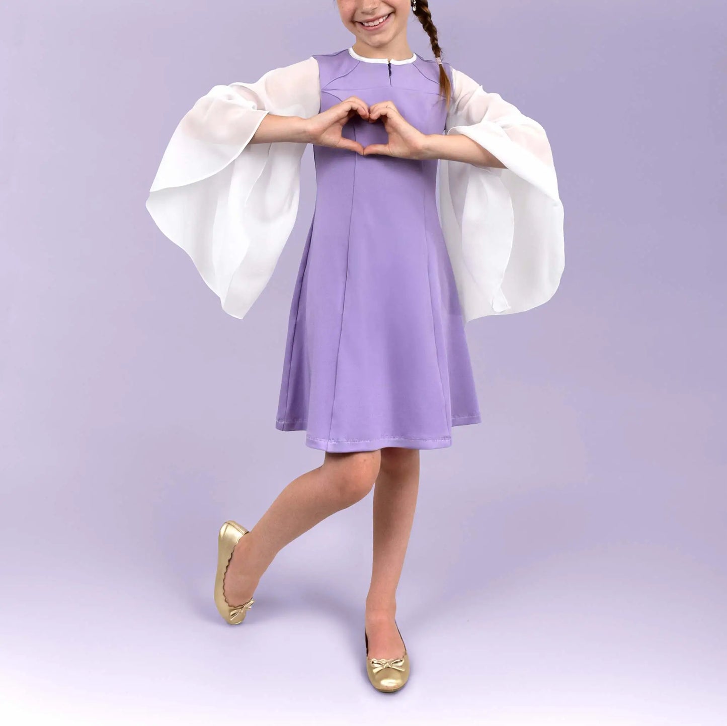Jeune fille en robe lilas à manches longues en voile blanc formant un cœur avec les mains devant elle - patron de couture Gaby de Kandix