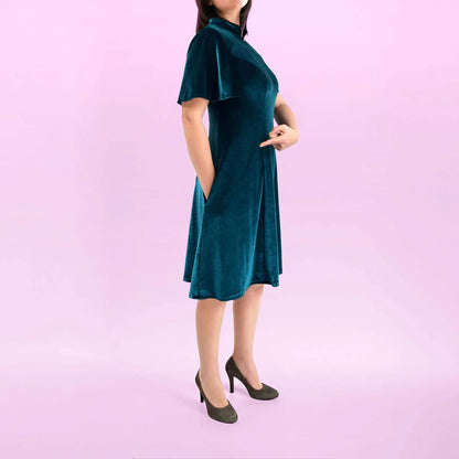 Vue de profil d’une femme en robe en velours vert, les mains glissées dans les poches - patron de couture Gaby de Kandix