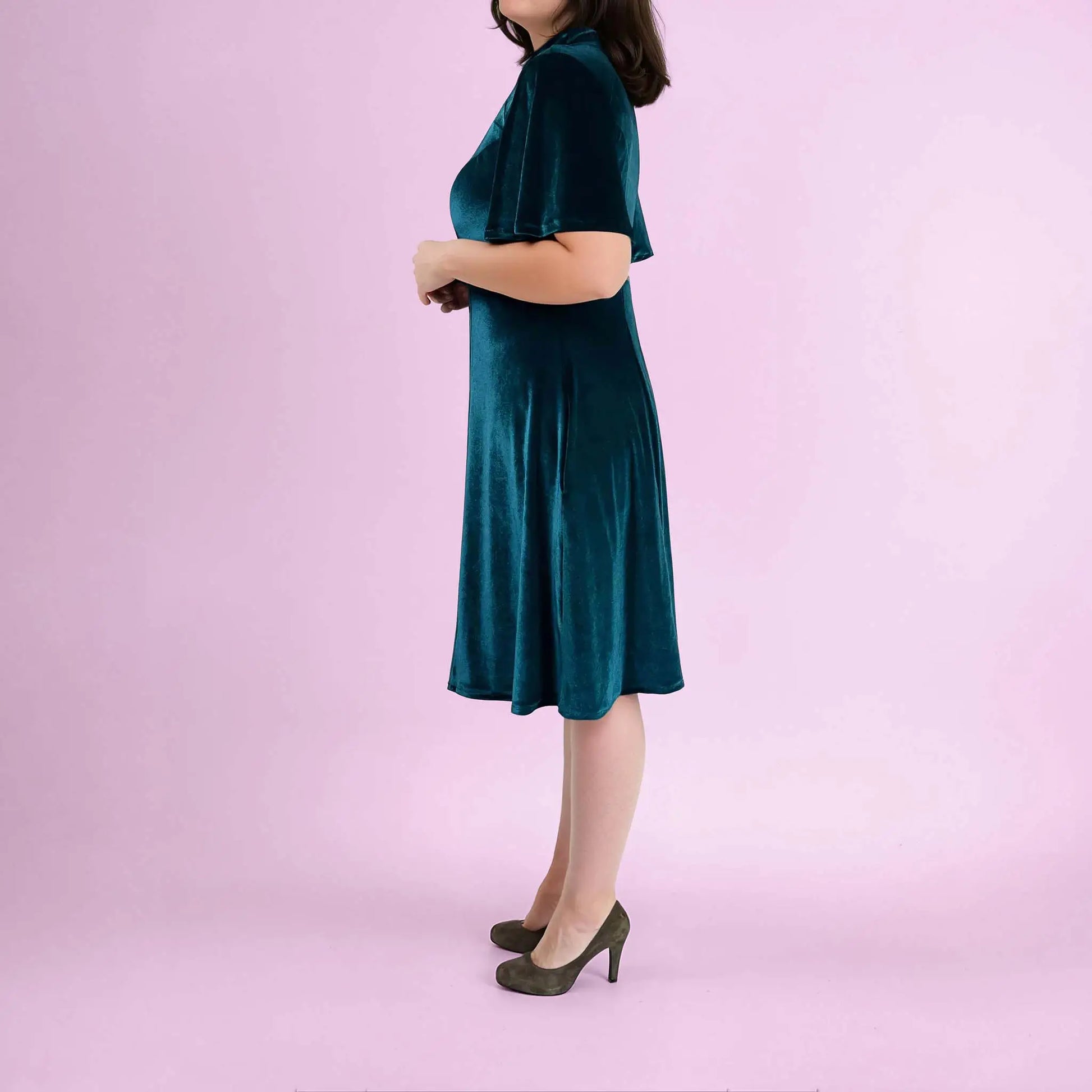 Femme en robe vert foncé en velours, debout de profil dans une pose naturelle - patron de couture Gaby de Kandix