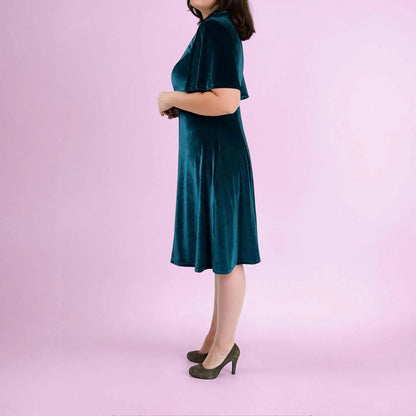 Femme en robe vert foncé en velours, debout de profil dans une pose naturelle - patron de couture Gaby de Kandix