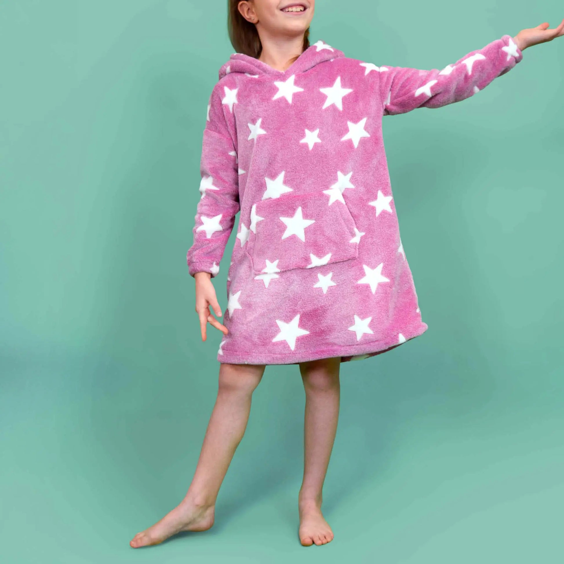 Enfant souriante en sweat Casimir rose à étoiles, en mouvement avec le bras tendu - patron de couture Kandix