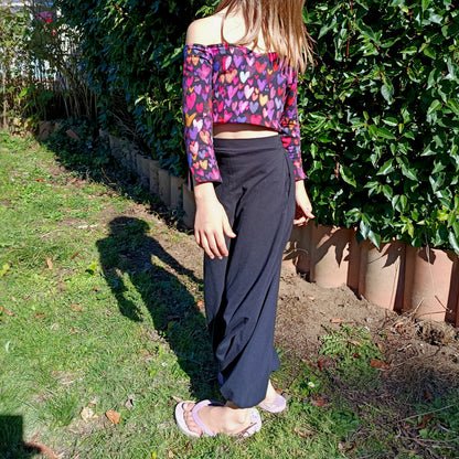 Top Yasmine enfant imprimé cœurs multicolore manches longues, porté avec pantalon noir, vue de profil en extérieur – patron Kandix