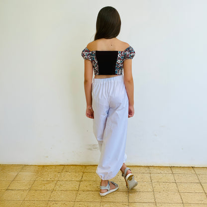 Top Yasmine enfant imprimé fleuri bleu et rouge avec dos en jersey noir, porté avec pantalon blanc, vue de dos – patron Kandix