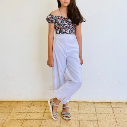 Top Yasmine enfant imprimé fleuri bleu et rouge avec manches courtes bouffantes, porté avec pantalon blanc, vue de face – patron Kandix