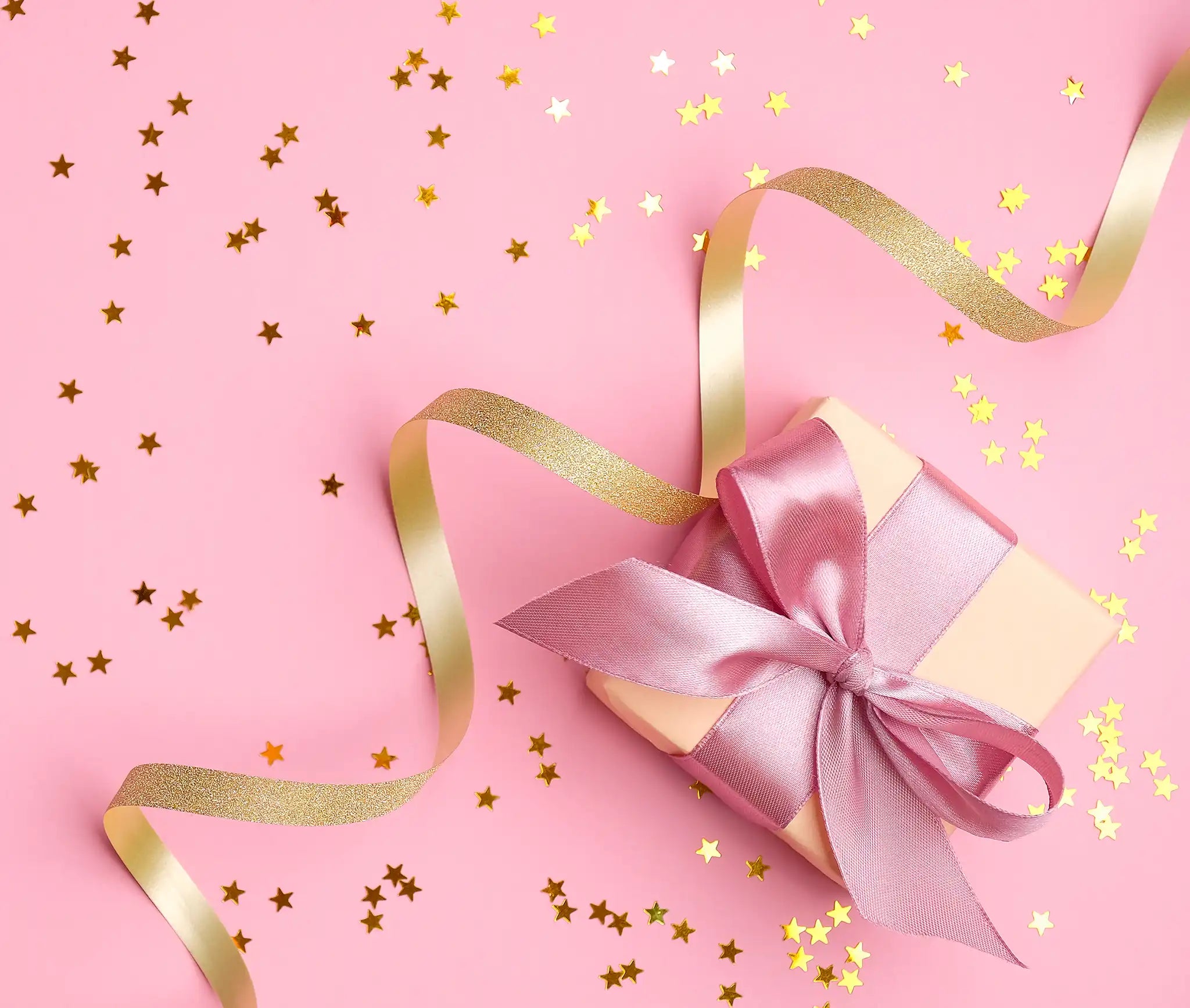 Paquet cadeau rose avec ruban en satin et étoiles dorées sur fond rose – patrons couture Kandix